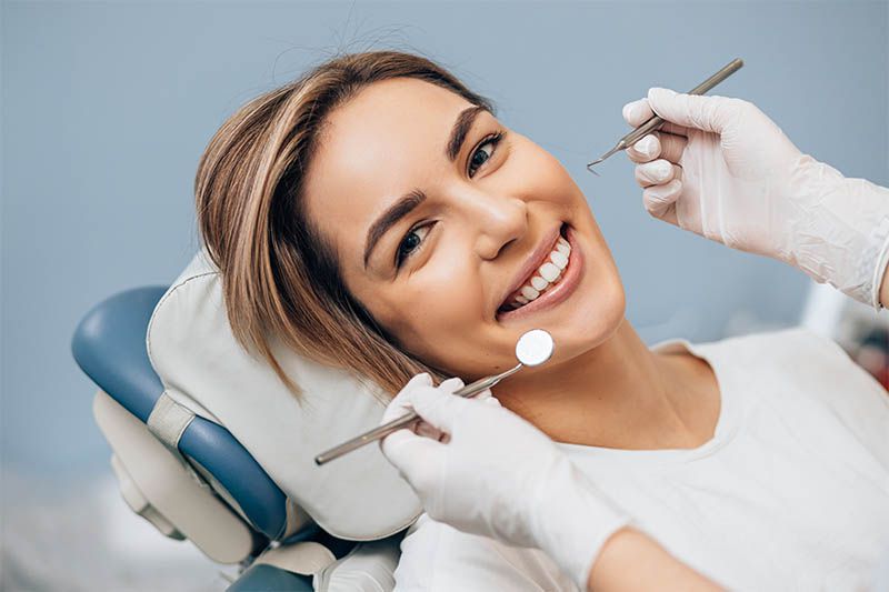uśmiechnięta kobieta podczas leczenia zębów